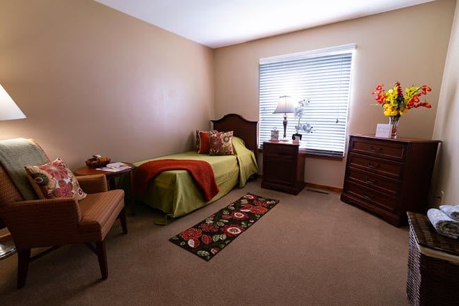 A cozy bedroom with a single bed, window, and wooden furniture.
