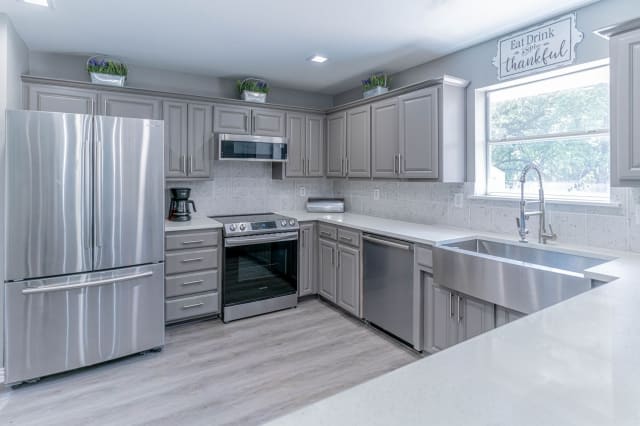 A modern kitchen with stainless steel appliances and gray cabinets.