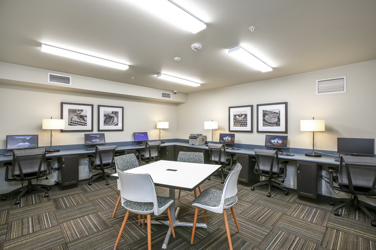 A modern office space featuring multiple computer workstations and a central meeting table.