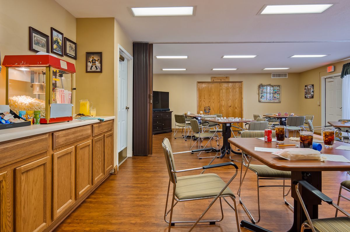 A casual dining area with tables and chairs, featuring wood flooring and ceiling lights.