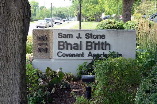 A sign for the Sam J. Stone B'nai B'rith Covenant Apartments, showcasing the building's identity in a landscaped area.