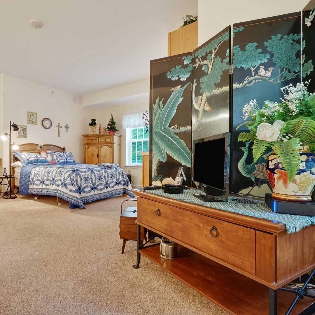 A classic styled bedroom featuring a screen divider, wooden furniture, and decorative plants.