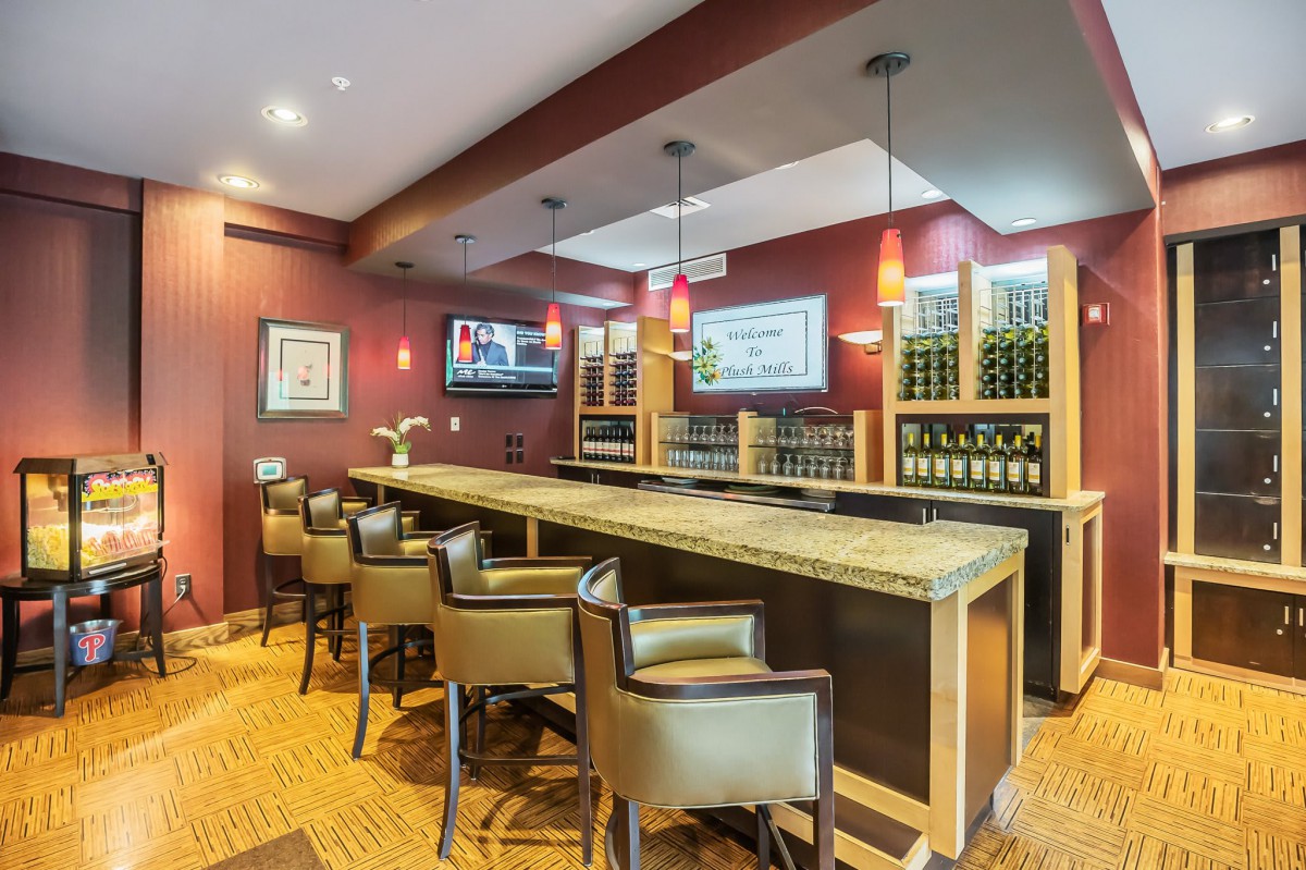 A modern bar interior featuring comfortable seating, a long counter, and wine bottles displayed on shelves.