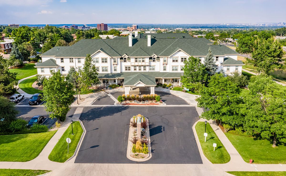 Aerial view of a large residential building with a landscaped driveway and surrounding greenery.