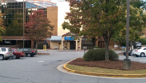 A view of a building entrance with surrounding trees and a parking area, showcasing an autumn atmosphere.