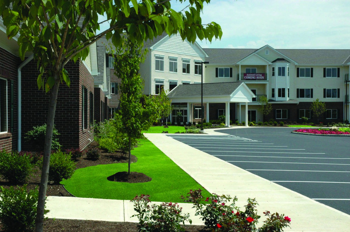 A modern building with a landscaped front and a parking lot.