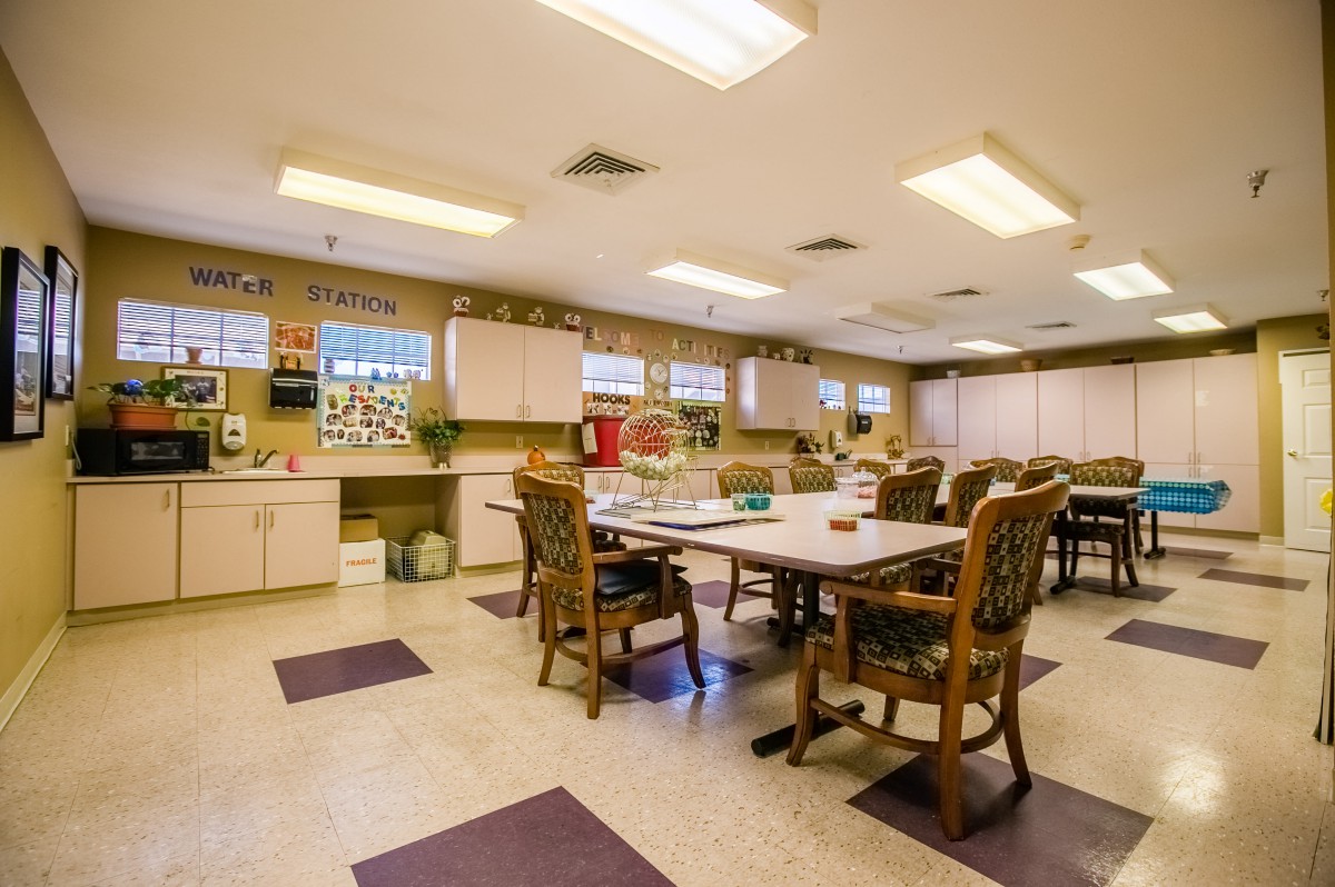 A well-lit kitchen and dining area with tables and chairs set up for communal use.