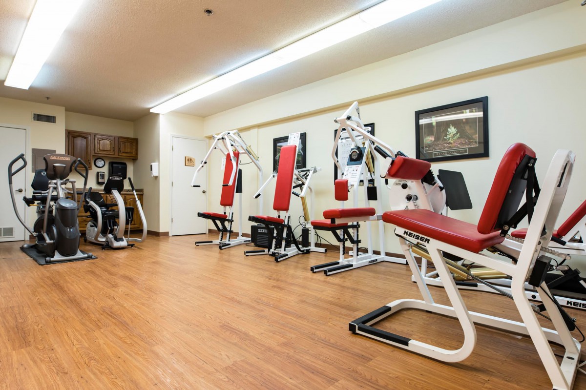 A well-equipped gym with exercise machines and red cushioned seats.