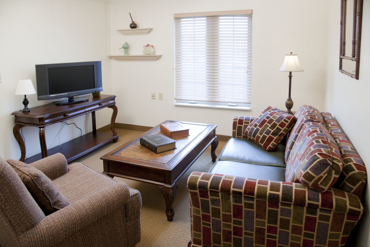 A cozy living room with a patterned sofa, coffee table, and television.