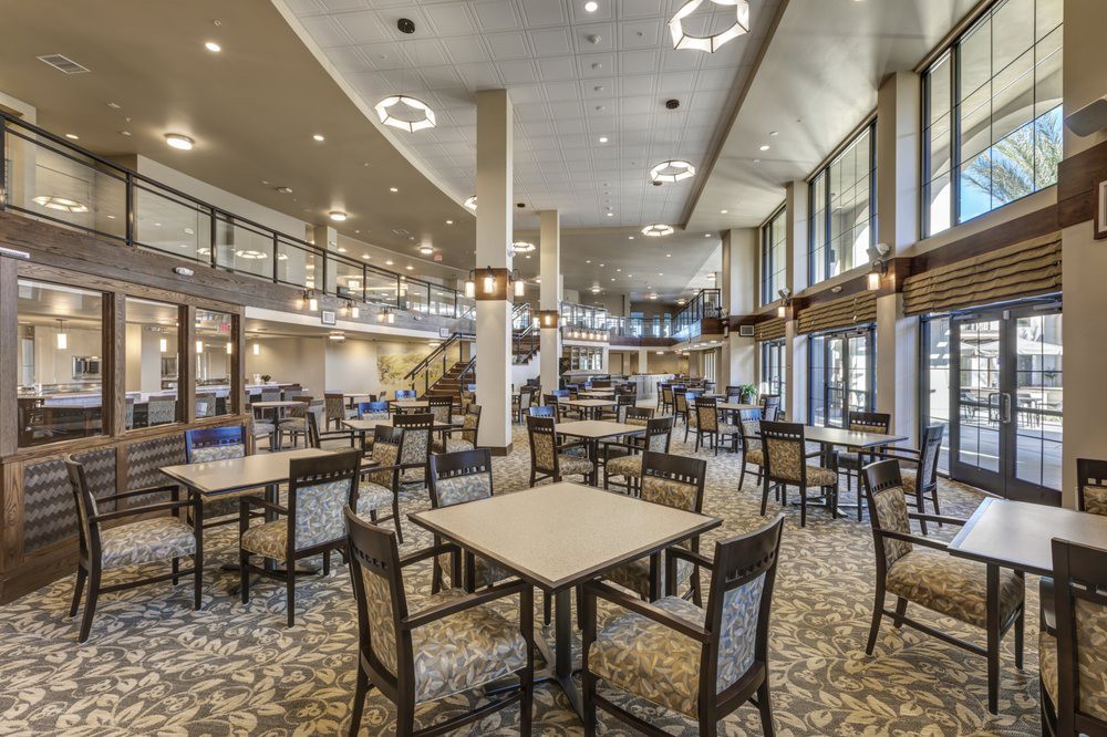 A spacious and modern dining area with tables and chairs arranged neatly under stylish lighting.