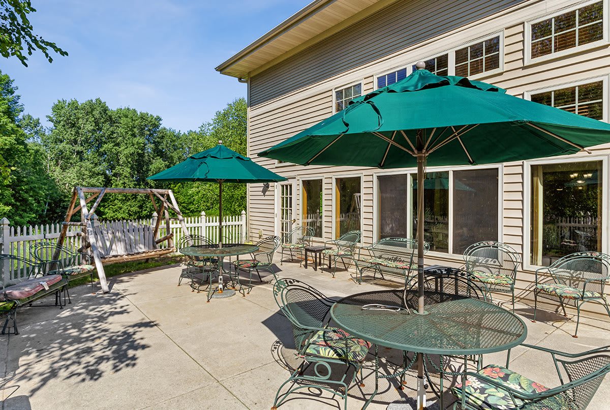 A sunny patio with tables and green umbrellas outside a building.