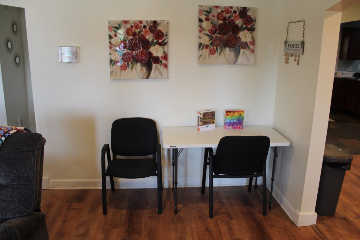 A small waiting area with two chairs and a table, decorated with artwork on the wall.