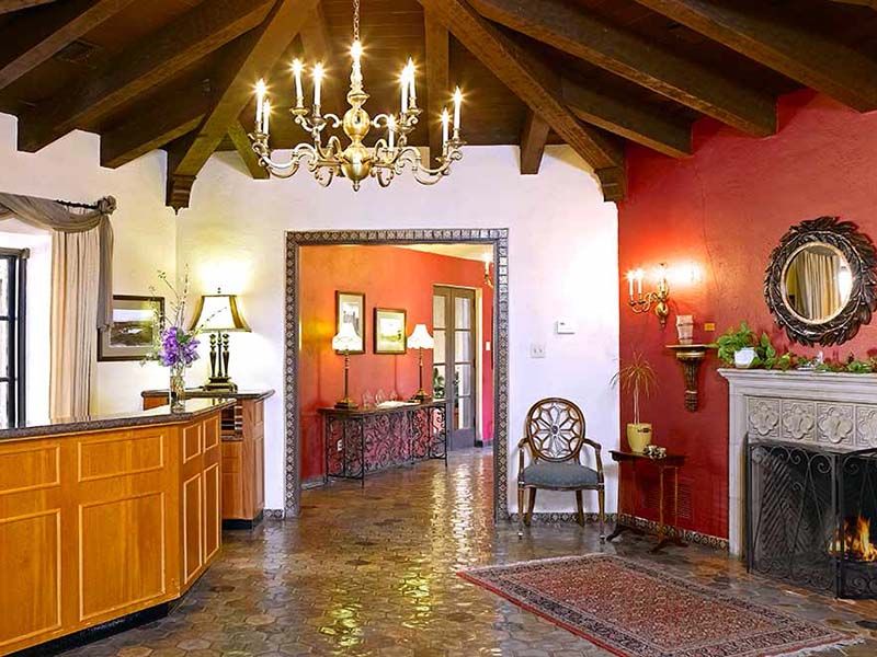A traditional living room featuring a chandelier, wooden beams, and a cozy fireplace.