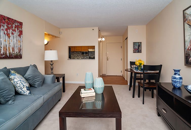 A cozy living room with a sofa, coffee table, and dining area in a modern apartment.