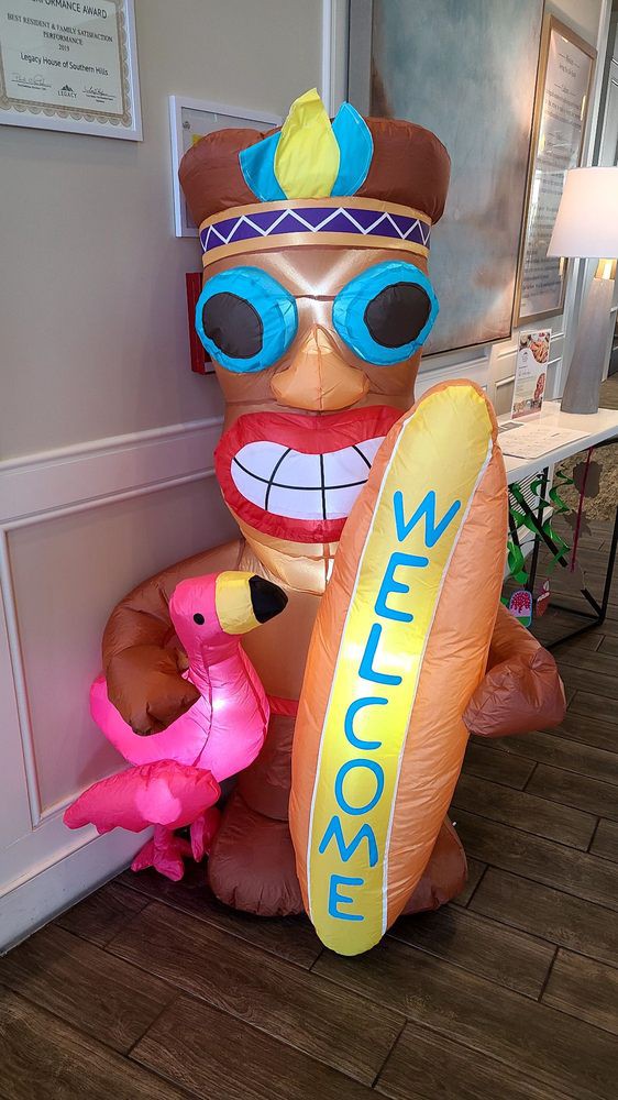 A vibrant inflatable decoration featuring a grinning character holding a welcome surfboard and a pink flamingo.
