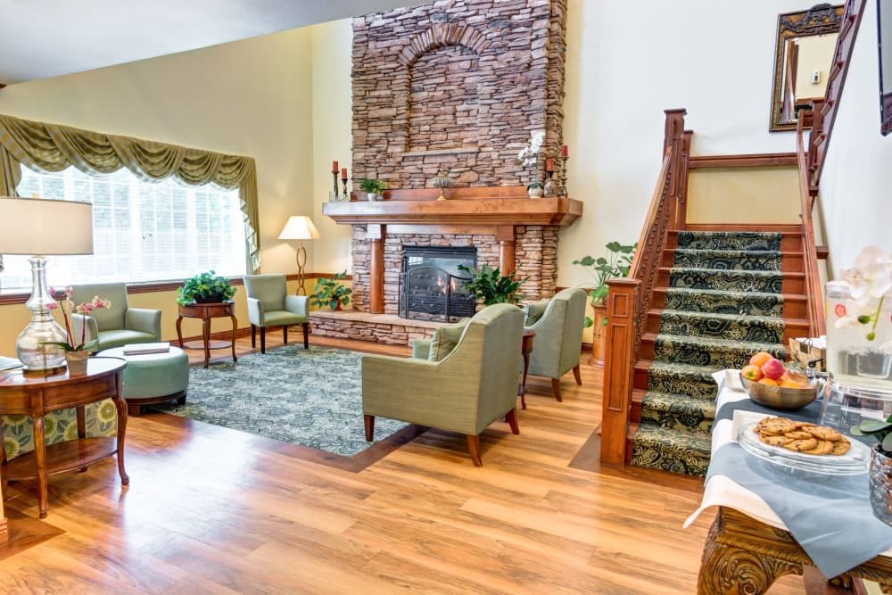 A cozy living room with a stone fireplace, comfortable seating, and hardwood flooring.