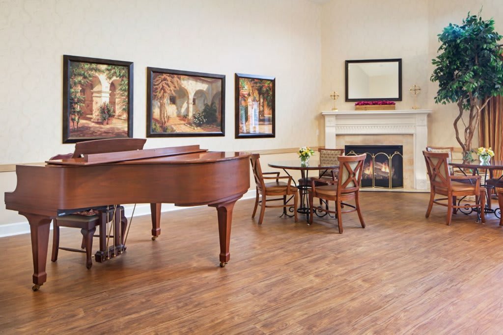 A stylish living room with a grand piano, elegant furniture, and artwork on the walls.