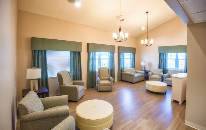 A cozy living room with armchairs and chandeliers, featuring wooden floors and elegant curtains.