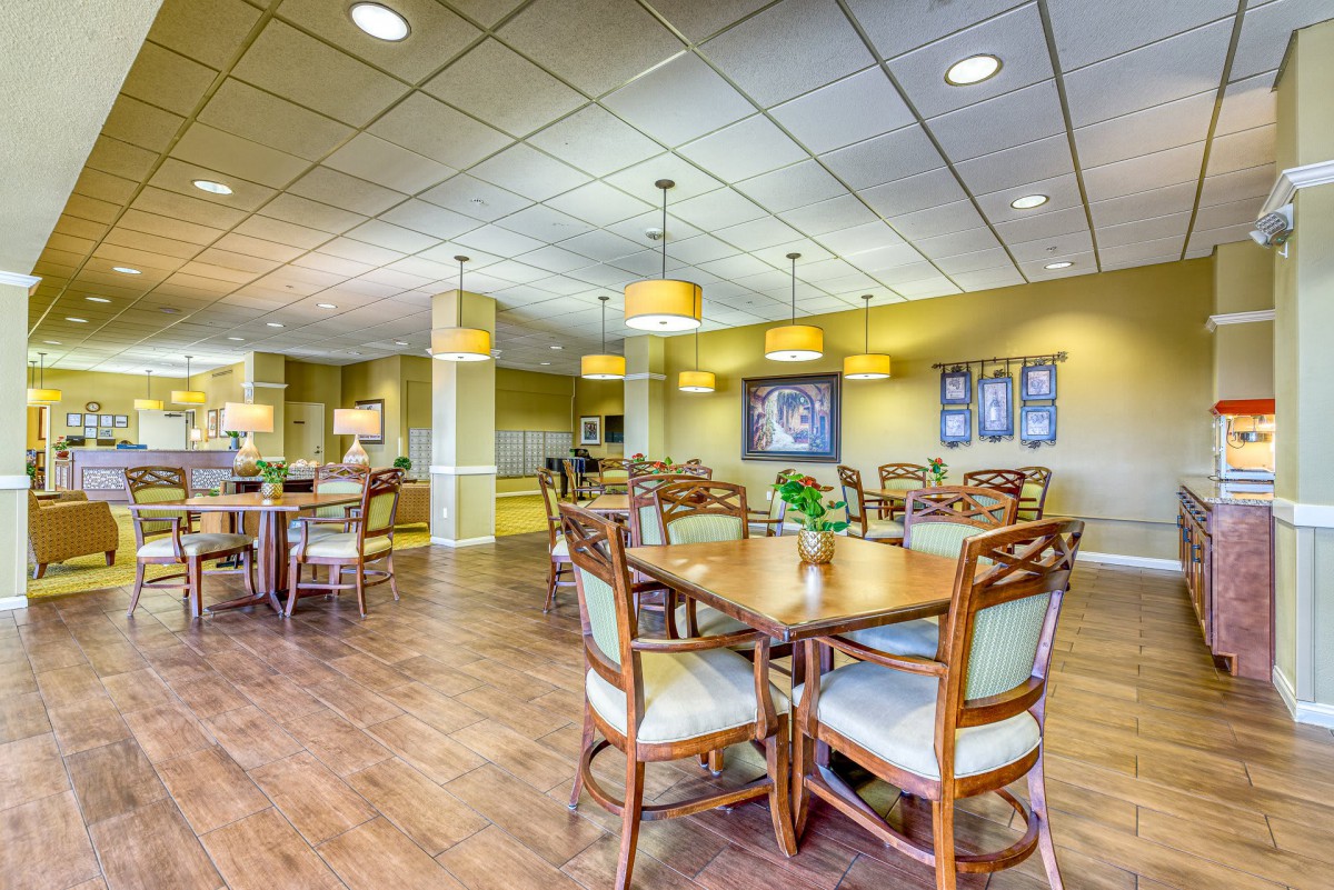 A spacious dining area with wooden tables and chairs, well-lit by ceiling lights.