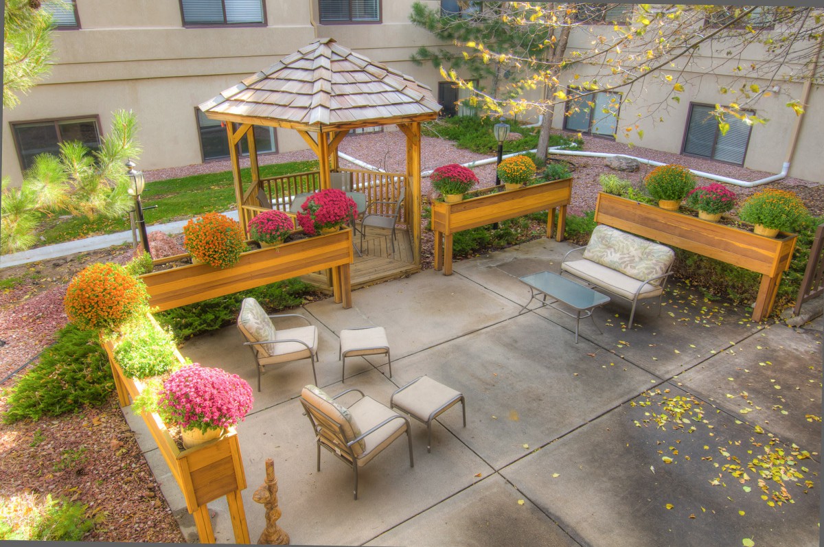 A cozy outdoor patio with a gazebo, seating area, and vibrant flowers.