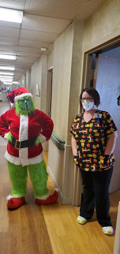 A festive moment captured in a healthcare setting with the Grinch and a nurse.