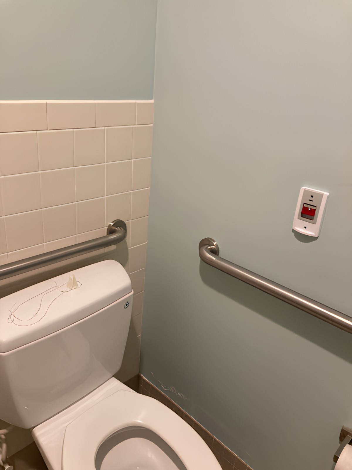 A bathroom with accessible handrails next to the toilet.