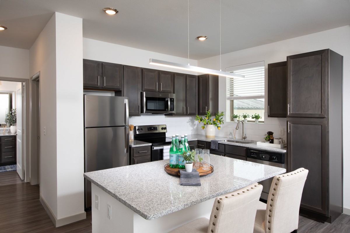A modern kitchen with stainless steel appliances and a granite island countertop.