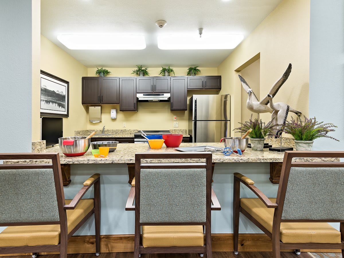 A modern kitchen with a sleek design, featuring bar stools at the countertop, stainless steel appliances, and decorative elements.