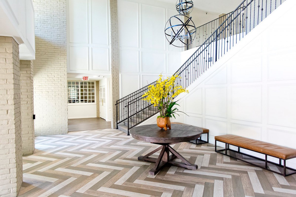 A modern lobby with a stylish staircase and a table adorned with yellow flowers.