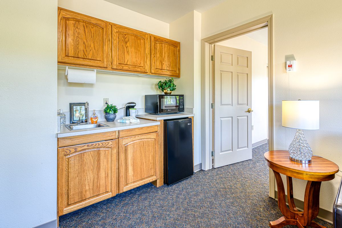 A compact kitchenette with wooden cabinets, a microwave, and a mini-fridge.