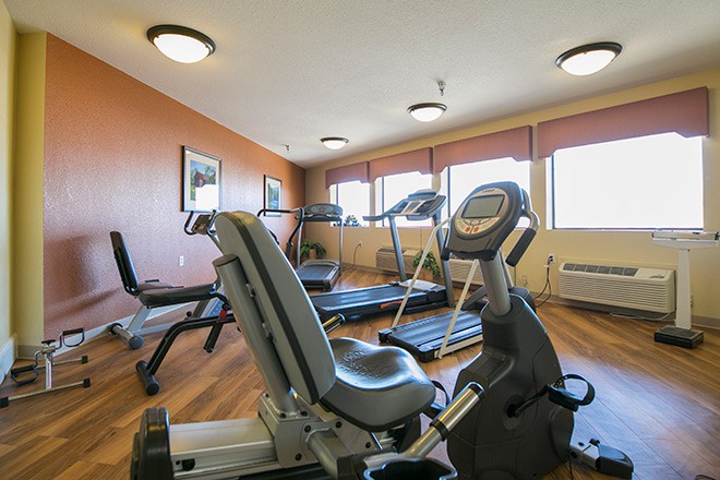 A well-lit gym with various fitness equipment including treadmills and a stationary bike.