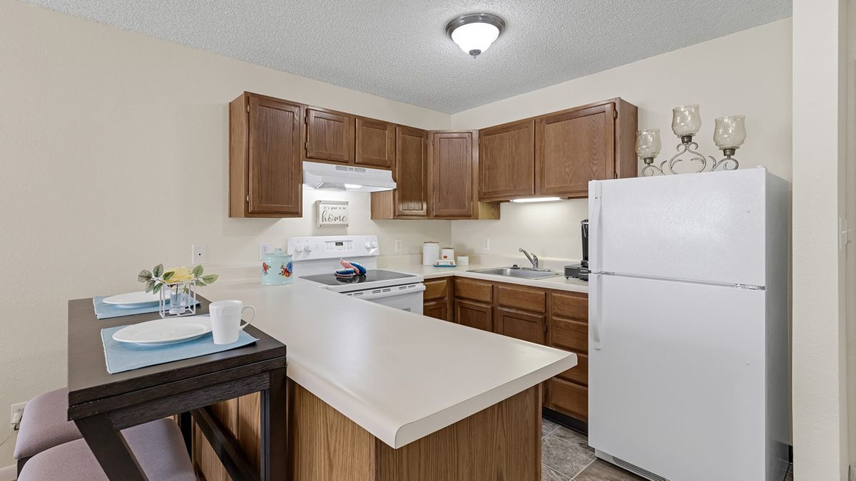 A modern kitchen interior with wooden cabinets and white appliances.