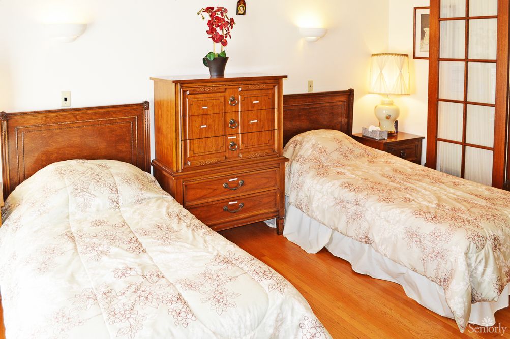 A cozy bedroom with twin beds and elegant wooden furniture.