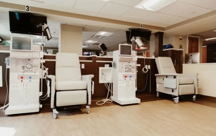 A medical clinic room equipped with dialysis machines and comfortable chairs.