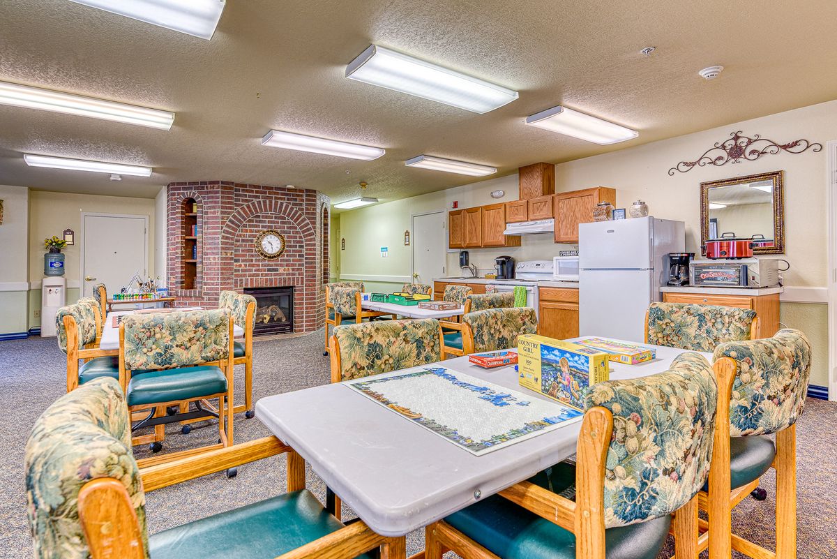 A cozy dining and kitchen area with tables, chairs, and kitchen appliances.