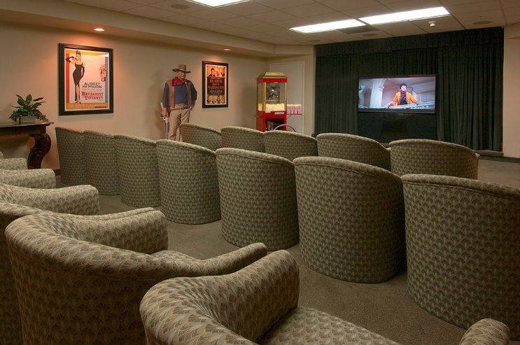 A cozy home theater setup with comfortable seating, a movie playing on the screen, vintage posters on the walls, and a popcorn machine.