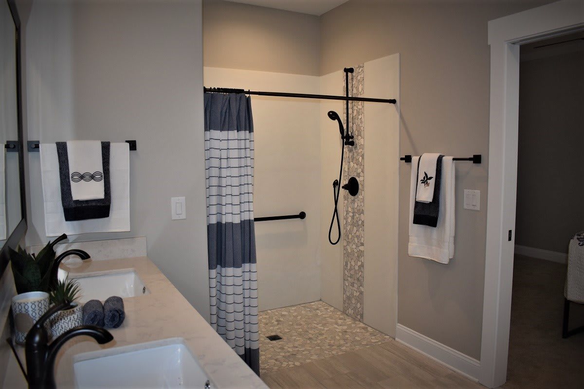 A modern bathroom with a walk-in shower, featuring neutral tones and minimalist decor.