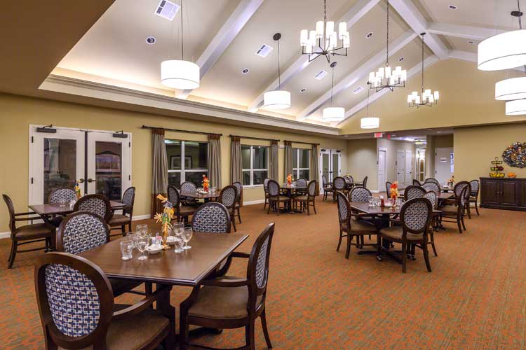 A spacious dining room with elegant furniture and chandeliers.