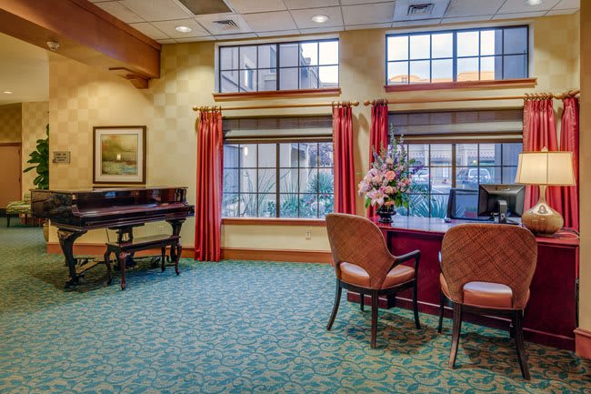 A well-decorated lobby area with chairs and a desk near large windows.
