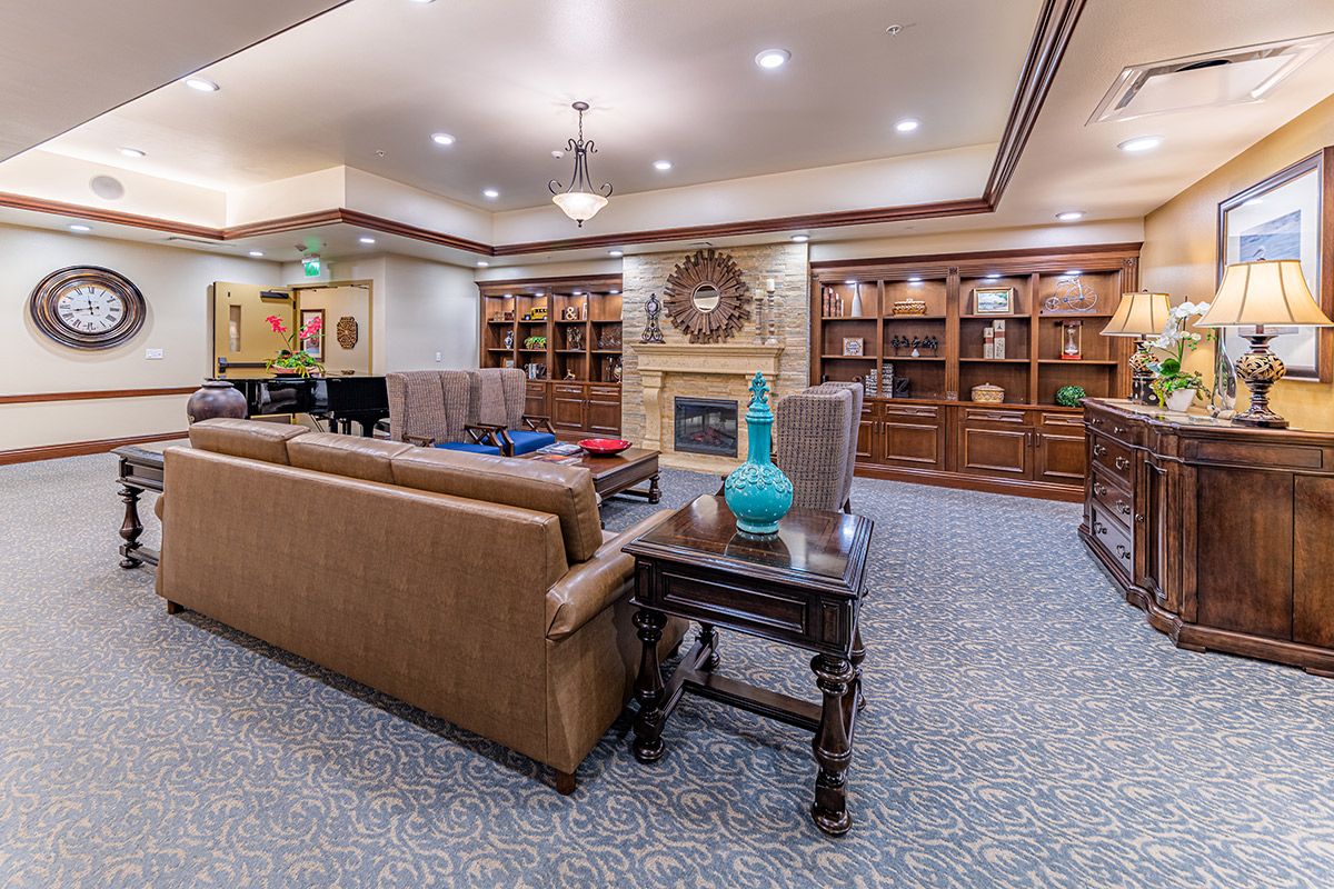 A spacious and elegantly furnished living room with sofas, a fireplace, and bookshelves.