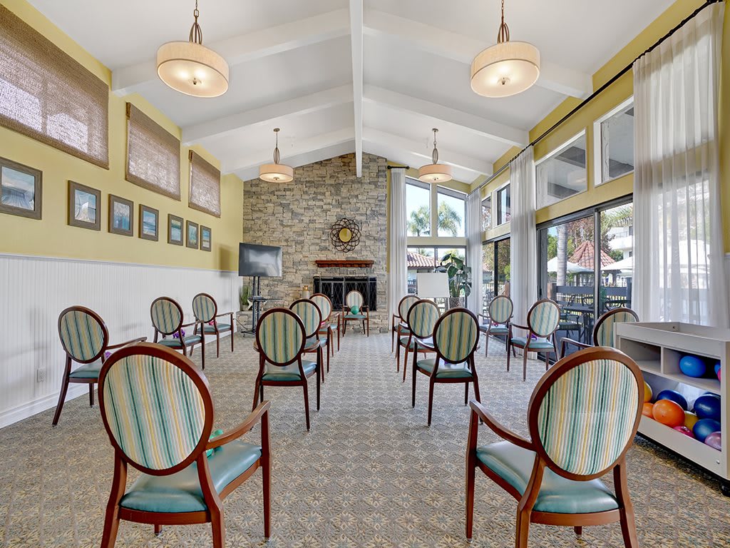 A spacious meeting room with elegant chairs arranged in rows, featuring a stone fireplace and large windows providing natural light.