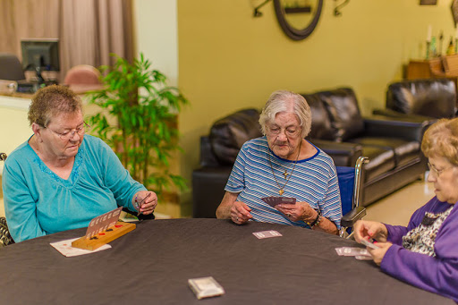 Three elderly women enjoy a card game together, sharing laughs and companionship.