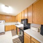 A modern kitchen with wooden cabinets and white countertops featuring various appliances.