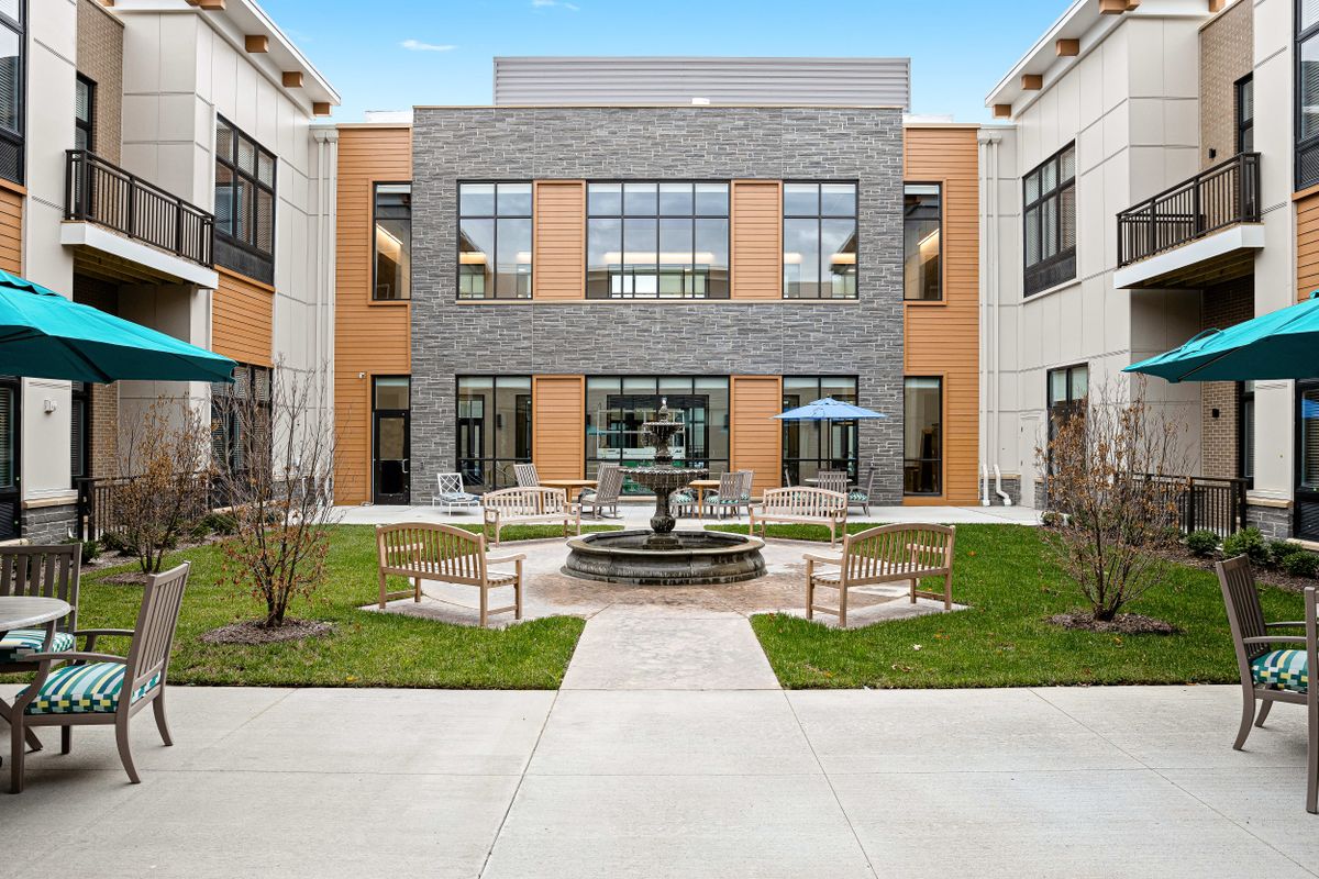 A modern courtyard with a central fountain and outdoor seating surrounded by a contemporary building.