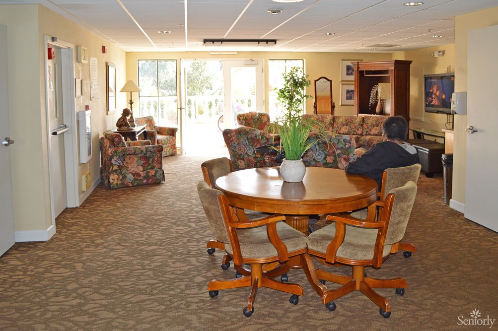 A cozy living room with a round table and chairs, surrounded by sofas and decorated with plants.