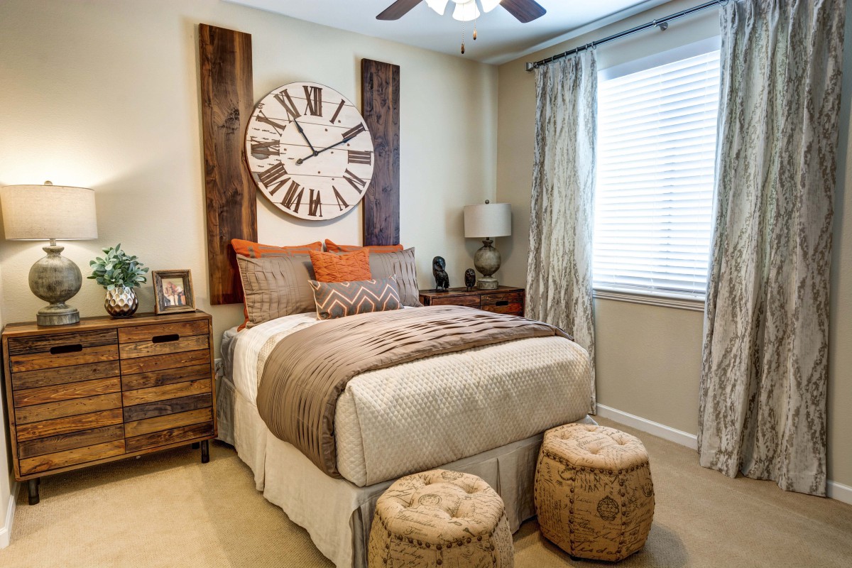 A cozy bedroom with warm tones and a large decorative clock above the bed.