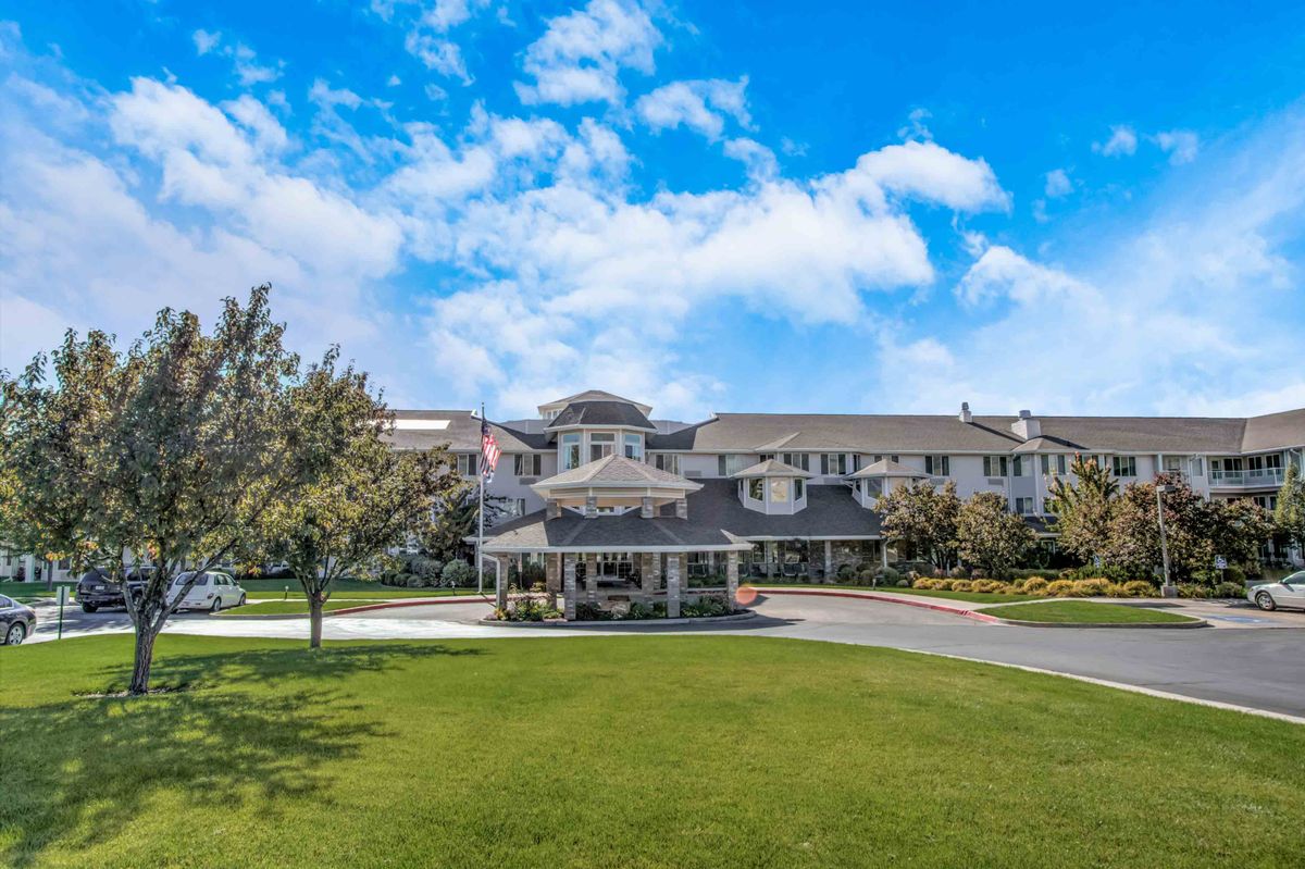 A large residential building with a well-manicured lawn and a bright blue sky overhead.