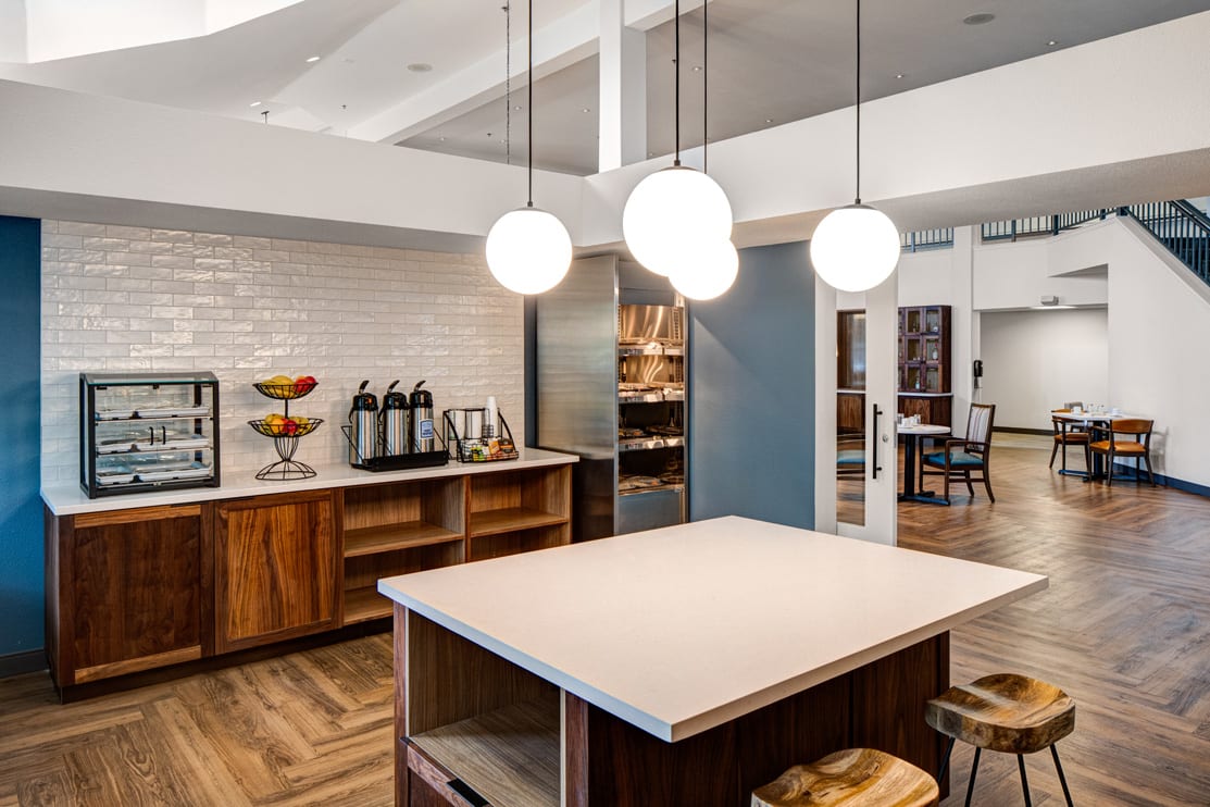 A modern kitchen with pendant lights, wood cabinetry, and an island countertop.