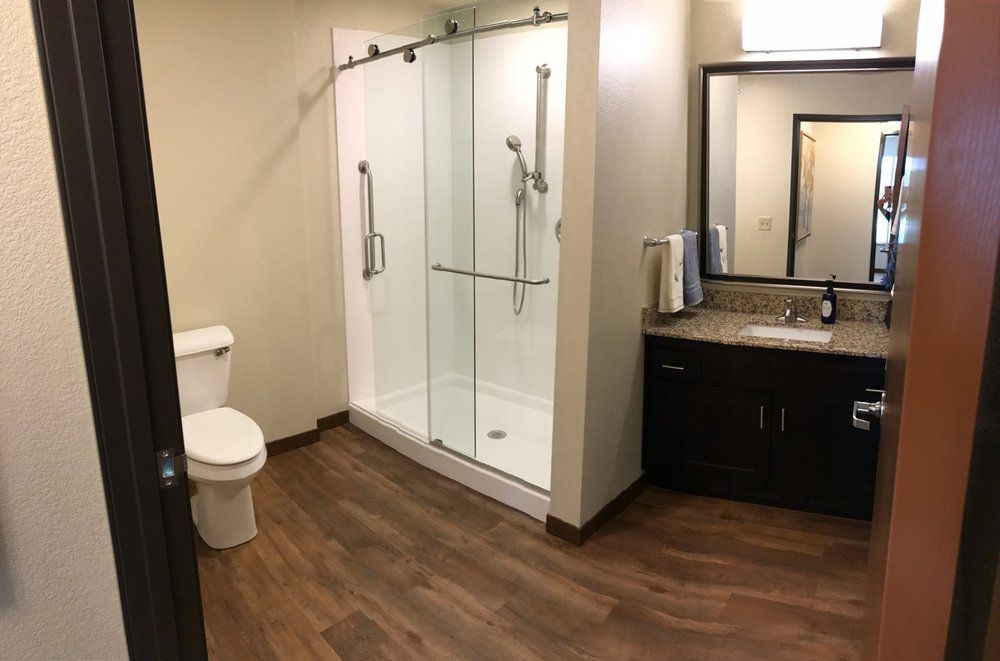 Modern bathroom with a glass shower and wood flooring.