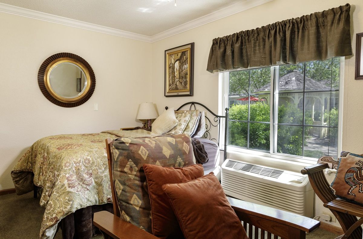 A cozy bedroom with a bed, decorative pillows, and natural light streaming in from a window.